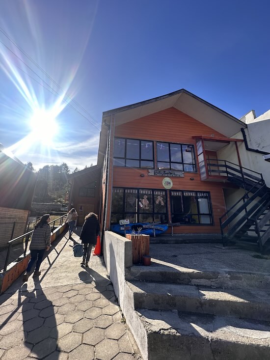 Fotografía exterior de una escuela. Se observa el sol brillando en la esquina superior derecha.